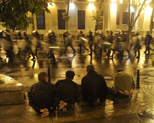 Detained protesters sit on the street as riot police leave after clashes in Tbilisi